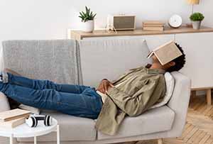 Man sleeping on couch with a book over his face.